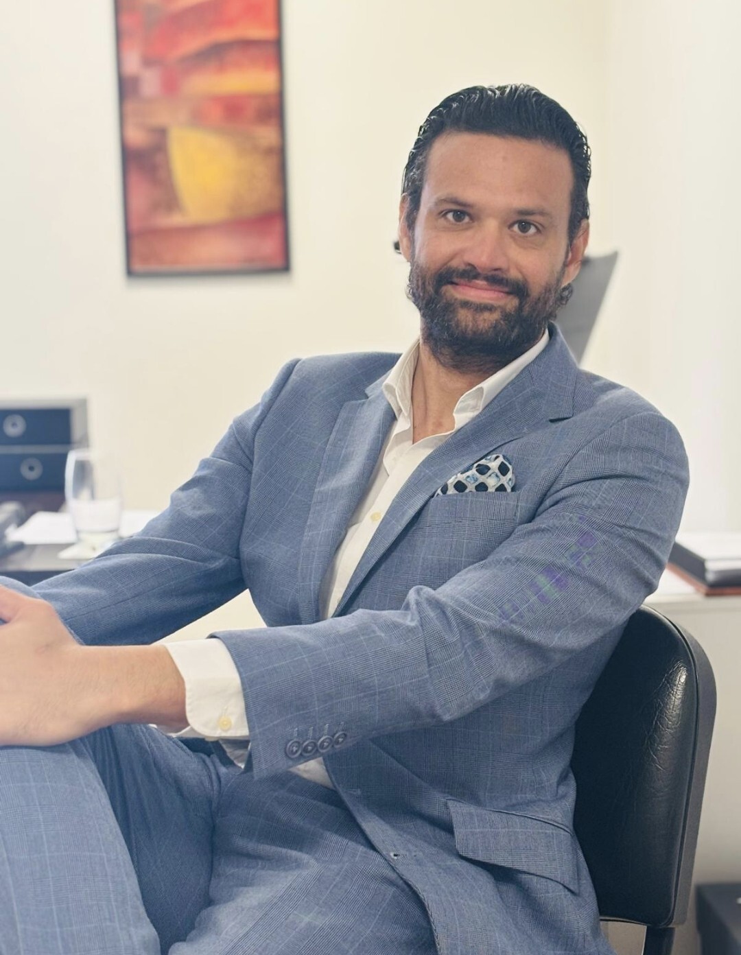 Filippo Arcaleni smiling in a grey suit with a patterned pocket square, seated in an office